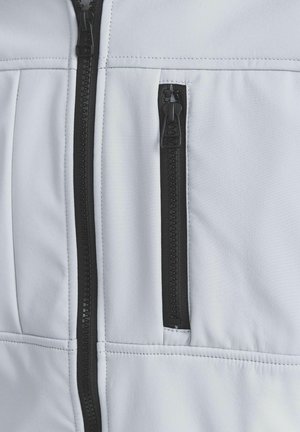 Biała kurtka z tkaniny z czarnym zamkiem błyskawicznym, teksturowana powierzchnia i mała kieszeń na zamek błyskawiczny na klatce piersiowej. Szwy są widoczne.