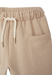 Beige Sweatpants mit elastischem Bund und Kordelzug, ausgestattet mit einer Vordertasche und einem glatten, strukturierten Stoff.