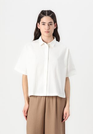 White short-sleeve button-up shirt with a textured fabric. Straight hem design, collared neckline, and subtle detail on the chest pocket.