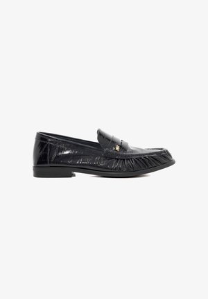 Mocassins en cuir verni noir avec des détails à franges et un bout arrondi. Présente un petit accent doré sur le dessus. Semelle en caoutchouc plate.