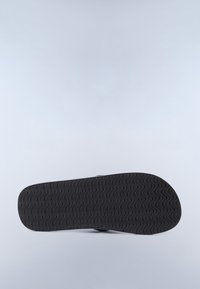 Suola di sandalo nera con motivo scanalato ondulato su sfondo grigio chiaro, posizionata orizzontalmente.