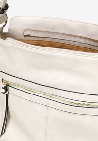 Borsa a mano in pelle beige chiaro con una tasca con cerniera sulla parte anteriore. Presenta accessori dorati, cuciture nere e una finitura morbida e texture.