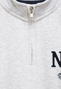 Šedá mikina na zips s rebrovaným golierom, s viditeľným zipsom a vyšitým logom "N" na prednej strane. Mäkká textúra.