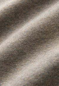 Tessuto di cotone, tonalità marrone chiaro con una sottile texture, caratterizzato da una superficie liscia e uniforme e una leggera elasticità per maggiore flessibilità.