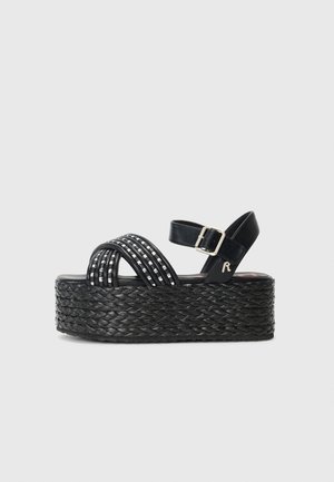 Sandalias negras de plataforma con suela de yute trenzado, tiras cruzadas con detalles metálicos y una correa ajustable en el tobillo.