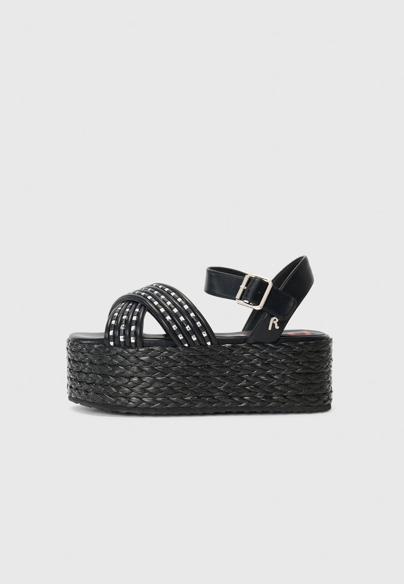 Sandales compensées noires avec semelle en jute tissé, lanières croisées avec accents métalliques, et une bride de cheville réglable.