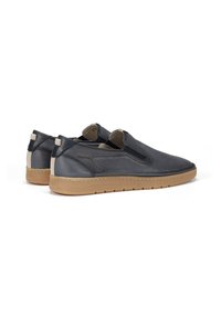 Zapatos tipo slip-on de cuero azul marino con detalles perforados, paneles elásticos, suelas de goma marrón y acentos beige en contraste.