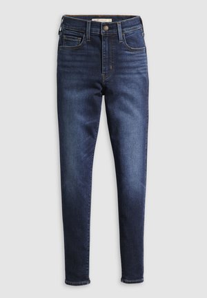 Jean bleu foncé avec une coupe slim, dotés d'une taille haute, de cinq poches et de coutures contrastantes. Texture de denim lisse et passants de ceinture standards.