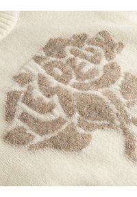Texturiertes cremfarbenes Sweatshirt mit einem beigen Rosendesign, feinen, weichen Fasern und einem gerippten Halsausschnitt, der das Muster und den Farbkontrast betont.