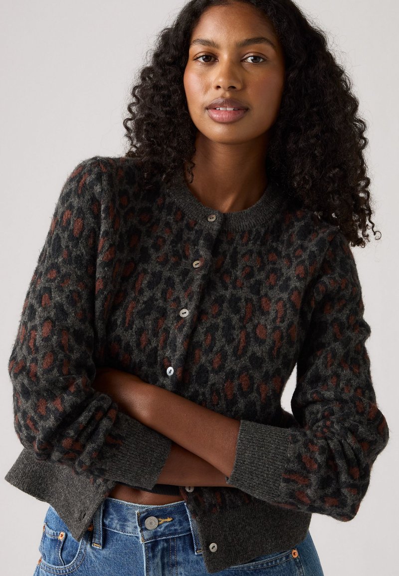 Dunkelgrauer Cardigan mit einem Leopardenmuster in Rost und Schwarz. Verfügt über einen runden Ausschnitt und Knopfverschlüsse und besteht aus einem weichen, strukturierten Material.