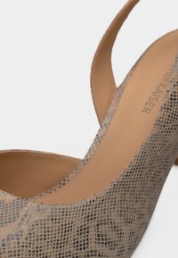 Chaussure à talon haut beige avec un motif texturé et une bride arrière, dotée d'un intérieur lisse couleur tan.