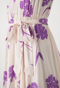 Vestito floreale caratterizzato da un tessuto beige chiaro decorato con motivi di fiori viola. Include un dettaglio in vita annodato, pieghe e una texture morbida.