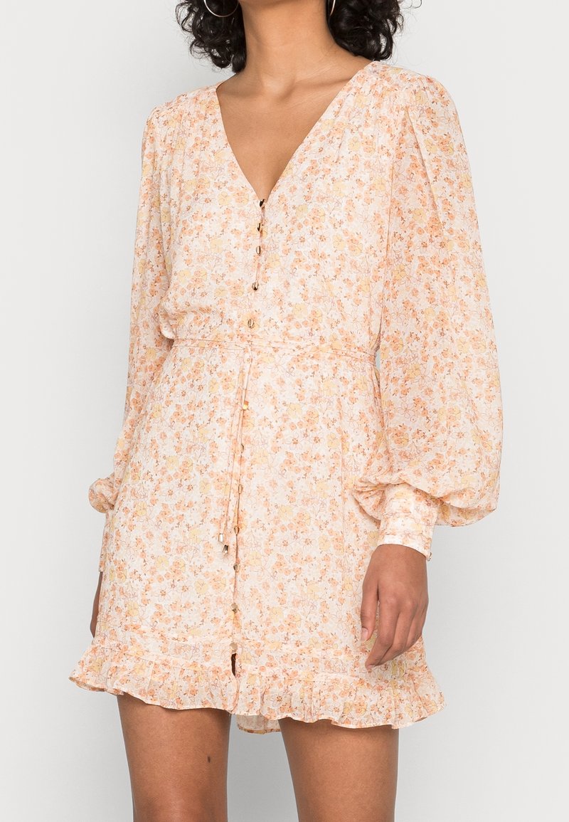 Blumenkleid in hellpfirsich mit langen Puffärmeln, V-Ausschnitt, Knöpfen in Goldoptik und einem rüschierten Saum, aus leichtem Stoff gefertigt.
