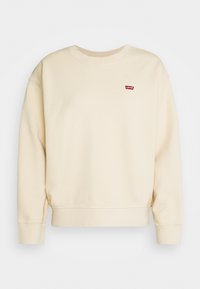 Sweat-shirt beige avec un col rond et des poignets côtelés. Dispose d'un petit logo Levi's rouge sur la poitrine gauche. Matière en coton doux.
