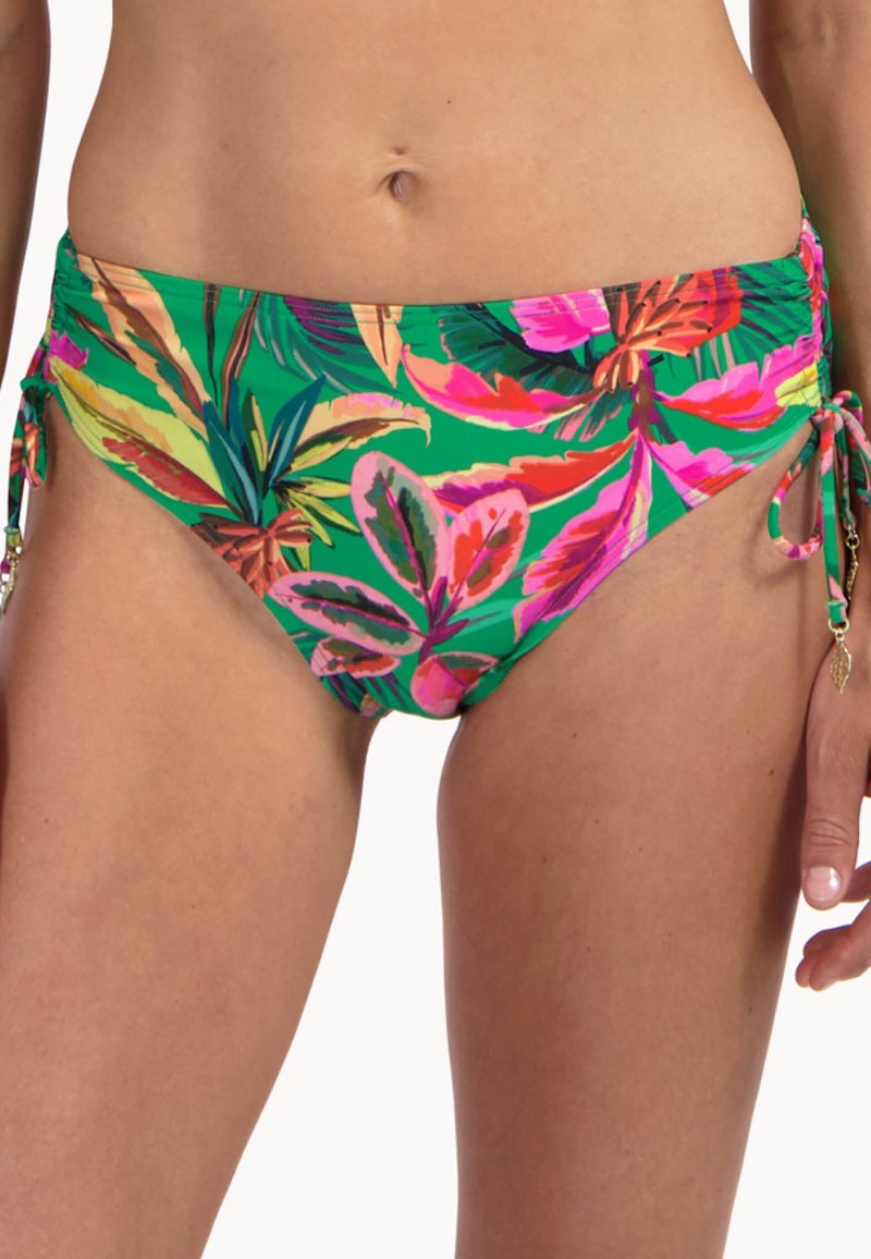 Slip bikini verde con motivi di foglie tropicali rosa acceso e arancioni, laccetti laterali con ciondoli a forma di foglia dorata, indossati da una persona con addome visibile.