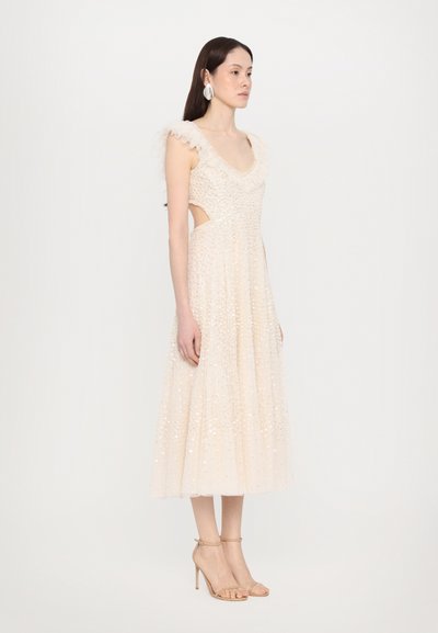 Valkoinen beaded midi-mekko, jossa on frillikaulus ja leikattuja sivuja, ominaisena virtaava hameosa ja käytettynä rengaspohjaisilla nude-koroilla.