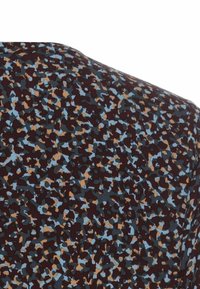 Das gemusterte Gewebe hat einen maronfarbenen Hintergrund mit blauen und braunen abstrakten Formen. Das Material wirkt glatt mit einem leichten Glanz.