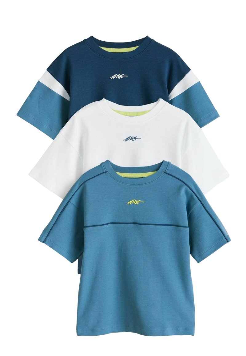 Trois t-shirts empilés : bleu marine avec des accents blancs, blanc avec du vert, et bleu sarcelle avec des détails bleus. Tissu en coton, coupe décontractée, manches courtes.