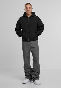 Musta vetoketjuhuppari, jossa on tilava istuvuus, suuri huppu ja etutaskut. Yhdistetty harmaisiin housuihin ja valkoisiin lenkkareihin. Yksinkertainen muotoilu ja neutraalit värit.