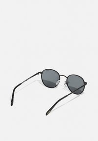 Gafas de sol de metal negro con lentes redondos, cristal tintado en gris y varillas delgadas. Incluye almohadillas nasales ajustables y detalles del logo en una de las varillas.