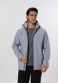 Veste légère grise, résistant à l'eau, avec une capuche, fermeture éclair à l'avant et poignets ajustables. Texture lisse, design minimaliste, idéale pour les activités de plein air.