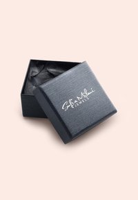 Svart smyckeskrin med strukturerad yta och silverlogotypen "Sofia Milani Jewels." Öppet, visar svart innerfoder och skrynklat silkespapper.