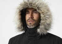 Fekete parka dzseki nagyméretű, szőrrel keretezett kapucnival, sima külső textúrával és gombos záródással a nyakán.