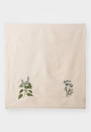 Beige stof met geborduurde groene en blauwe botanische ontwerpen aan beide zijden. Gladde textuur, vierkante vorm, gedetailleerde bladeren en bloem patronen.