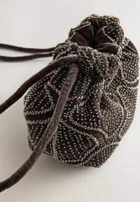 Sac de catifea maro închis cu șnur, decorat cu detalii din mărgele argintii, având o formă rotundă și o finisare moale la atingere.