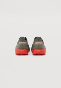 Baskets de sport vertes et noires avec une tige texturée, semelles oranges et accents réfléchissants. Conçues pour le confort et le soutien.