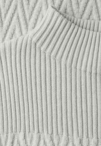 Maglione lavorato a maglia color grigio chiaro con un motivo a zigzag testurizzato e collo a coste. Il tessuto appare morbido e soffice, evidenziando una profondità nel design.