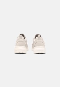 Chaussures de sport gris clair avec dessus en tissu lisse, col rembourré et semelle blanche contrastante. Design minimaliste avec languette à l'arrière.