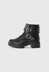 Black leather ankle boots with two gold buckles, textured upper, rugged rubber sole, and zipper closure at the back for easy wear.