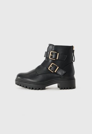 Botas de tobillo de cuero negro con dos hebillas doradas, parte superior texturizada, suela de goma resistente y cierre con cremallera en la parte posterior para facilitar su uso.
