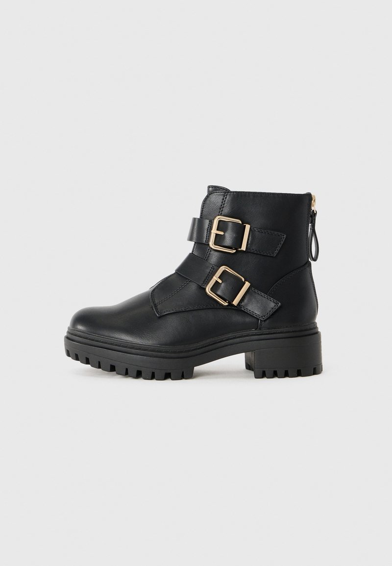 Black leather ankle boots with two gold buckles, textured upper, rugged rubber sole, and zipper closure at the back for easy wear.
