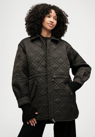 Προϊόν από καπιτονέ μαύρο μπουφάν με σχέδιο γιακά, μπροστινό φερμουάρ και ελαστικούς καρπούς. Διαθέτει διαγώνιες ραφές και δύο πλάγιες τσέπες.