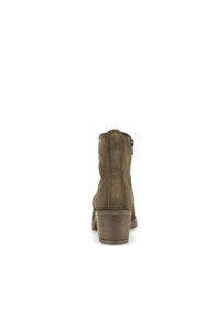 Botas de ante marrón hasta el tobillo con un tacón apilado, detalle de cremallera lateral y punta redondeada. La textura es suave con costuras sutiles.