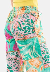 Pantalones coloridos, ligeros y estampados con cintura ajustable. Presenta diseños florales y paisley en tonos de azul verdoso, rosa y naranja.