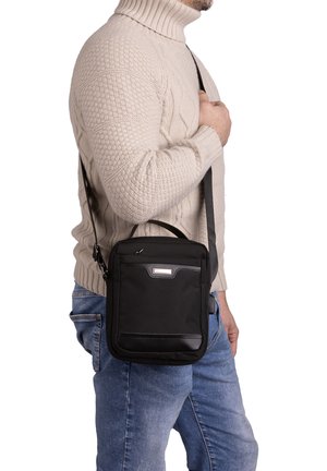 Borsa a tracolla nera realizzata in materiale resistente, con forma rettangolare, manico superiore e tracolla lunga e regolabile.