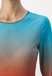 Abito a maniche lunghe con un motivo a gradiente che passa dal blu all'arancione. Tessuto morbido e elasticizzato con scollatura rotonda bordata di nero.