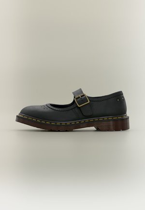 Chaussure Mary Jane en cuir noir avec bride à boucle, perforations florales décoratives et semelle épaisse marron avec surpiqûres jaunes.