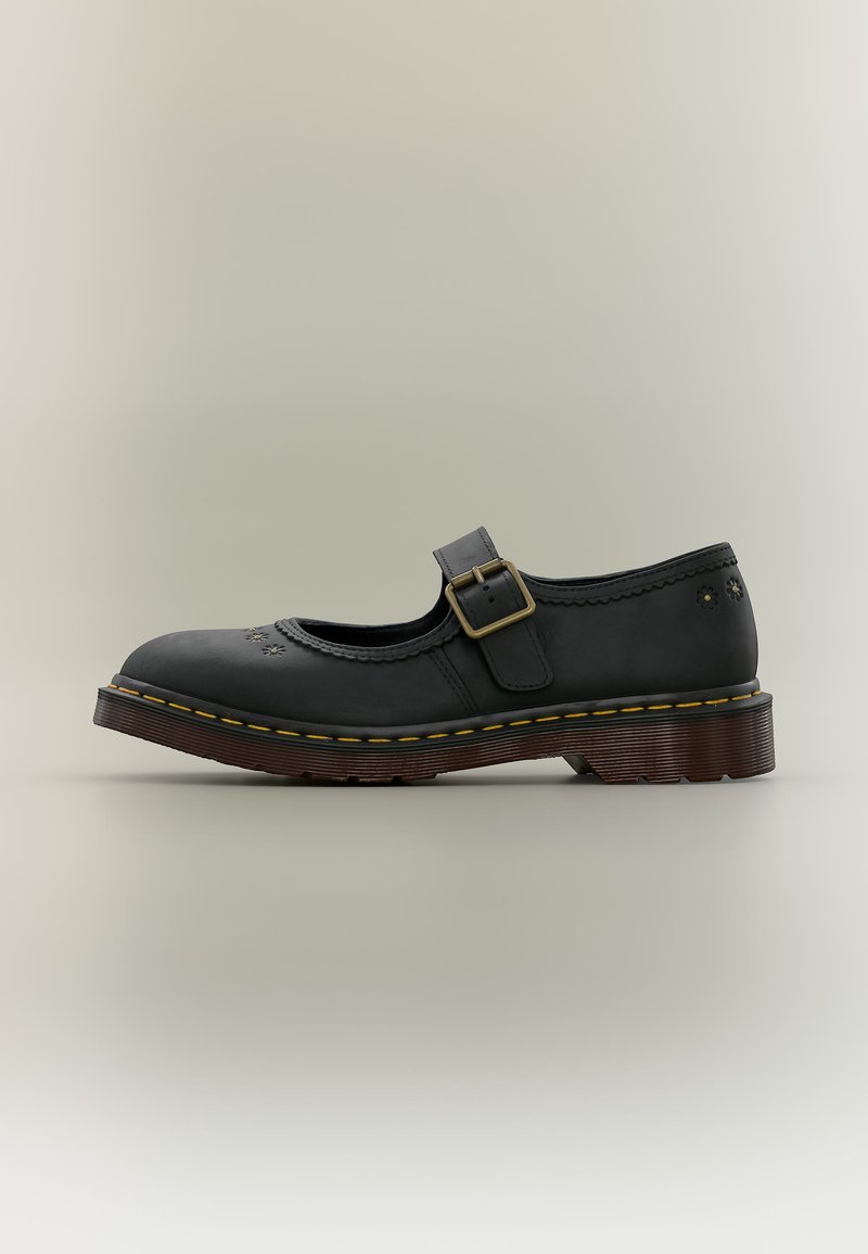 Scarpa Mary Jane in pelle nera con cinturino con fibbia, perforazioni decorative floreali e suola marrone spessa con cuciture gialle.