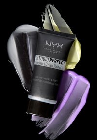 NYX Studio Perfect Photo-Loving Primer in a black tube with silver accents. Background features textured smears of gray, yellow, and purple.