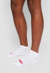 Fehér bokazoknik lélegző anyagból, elöl piros "Levi's" logóval. Rugalmas szegéllyel és texturált részletezéssel rendelkezik.