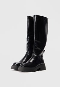 Czarne skórzane buty do kolan o błyszczącej powierzchni, zaokrąglonym czubku, grubym podeszwie i detalach szewnych. Gładka tekstura z minimalnymi akcentami.