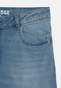 Svetle modré džíny s klasickým střihem, s přední kapsou a metalickými doplňky. Materiál má hladkou texturu a mírně vybledlý vzhled.