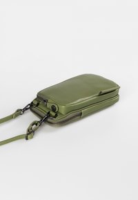 Green synthetic leather crossbody bag with a zippered closure, flat shape, detachable strap, and black metal hardware accents.
