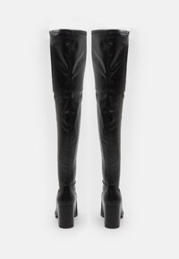 Botas de cuero negro por encima de la rodilla con una textura suave, tacones cuadrados y costuras contrastantes en la parte superior.