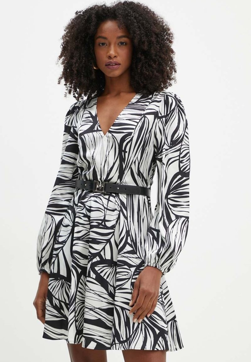 Abito in bianco e nero con motivo fogliare, scollo a V profondo, maniche lunghe a sbuffo e una cintura nera in vita, caratterizzato da una silhouette svasata.