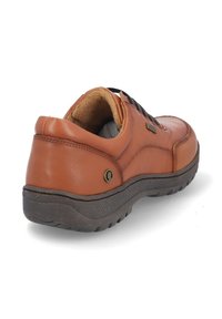 Zapato casual de cuero marrón con suela negra, con cuello acolchado y forro de piel, mostrado desde un ángulo trasero sobre fondo blanco.